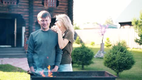 Travelling-A-young-guy-with-a-girl-standing-near-the-barbecue-in-which-coals-are-smoking