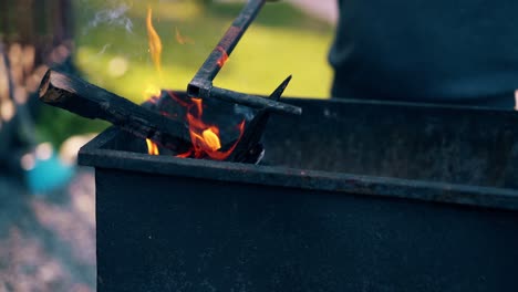 Close-up-Man-prepares-the-coals-in-the-grill-stirs-them-with-a-stick