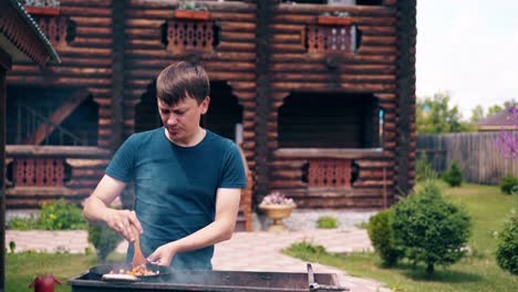 Young-man-makes-pilaf-in-a-cauldron-on-a-grill-on-an-open-fire-Stir-the-meat-and-carrots