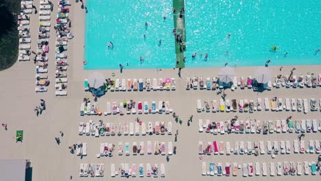Aerial-Flying-over-the-beach-a-lot-of-people-are-sunbathing-swimming-in-the-pool
