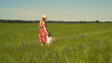 Slow-motion-Young-mother-in-red-dress-which-flutters-in-the-wind-dressing-hat-walks-along-the-endless-field