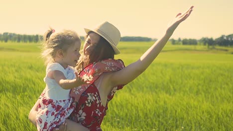 Close-up-Slow-motion-Young-mother-in-red-dress-wearing-hat-She-holds-little-daughter-in-her-arms