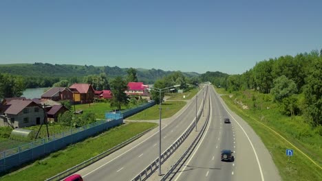 Luftflug-über-Der-Autobahn,-Blick-Auf-Den-Türkisfarbenen-Bergfluss,-Auch-Sichtbare-Touristenstadt,-Birkenstromleitungen,-Autos