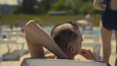 Back-view-Close-up-Bald-married-Italian-man-is-lying-on-beach-on-deck-chair