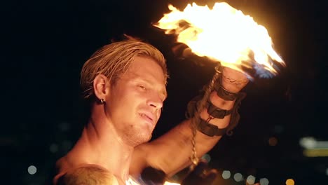 Young-blond-male-spins-two-burning-pois-around-face-Slow-motion-shot-Close-up-shot