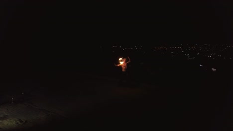 Young-blond-male-does-tricks-with-fire-spins-two-burning-torches-at-night-on-black-background-Tracking-shot