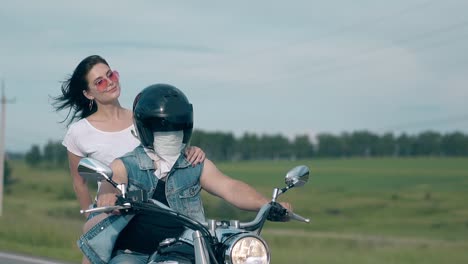 young-couple-rides-black-motorbike-along-road-at-field