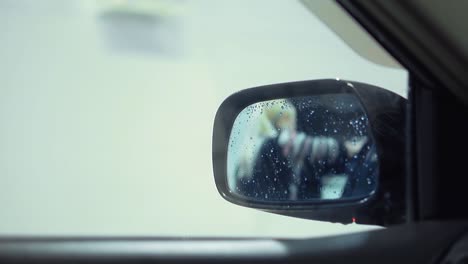 Girl-wiping-car-with-rag-View-through-rear-view-mirror
