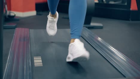 close-view-woman-legs-in-white-sneakers-on-modern-treadmill