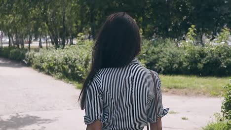 slow-motion-backside-view-slim-woman-walks-in-green-park