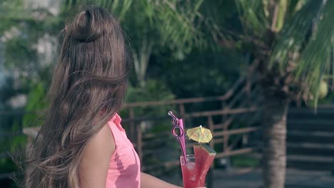 pretty-brunette-in-pink-blouse-holds-cocktail-with-straws