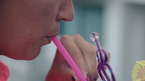 lady-drinks-cool-refreshing-beverage-through-plastic-pink-straw