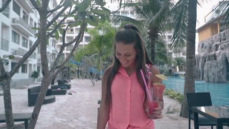 long-haired-girl-with-drink-in-hand-walks-at-hotel-smiling