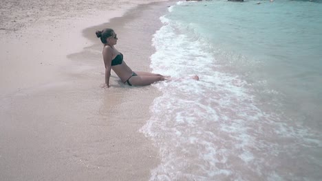 Wellen-Ergießen-Sich-über-Die-Beine-Einer-Frau-Mit-Haarbündel-Und-Sonnenbrille