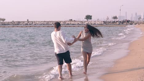 joyful-girl-and-guy-turn-and-join-hands-in-waves-slow-motion
