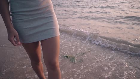 attractive-woman-in-dress-walks-along-surf-line-slow-motion