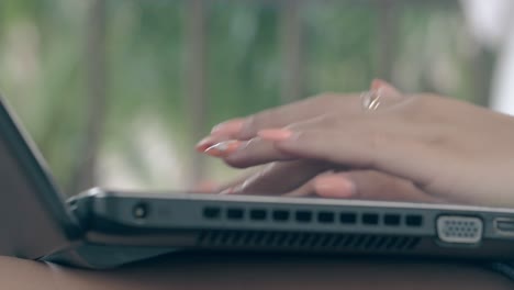woman-fingers-with-manicure-and-ring-type-on-laptop-closeup