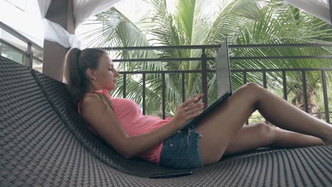 freelancer-with-ponytail-in-shorts-leans-on-lounger-back