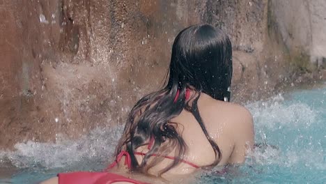 girl-with-long-dark-hair-lies-under-waterfall-enjoying-rest