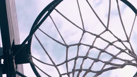 throwing-ball-into-basket-against-sky-with-clouds-closeup