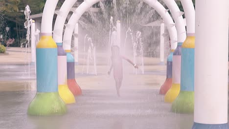 little-girl-runs-under-colorful-water-jets-arches-in-park