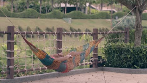 woman-with-long-legs-rests-in-hammock-at-resort-slow-motion