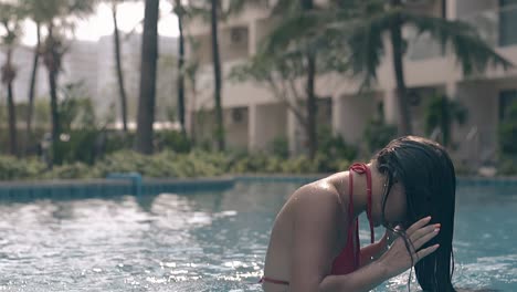 woman-cleans-face-and-fixes-hair-in-pool-slow-motion