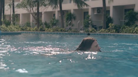 graceful-lady-swims-in-empty-pool-at-resort-slow-motion