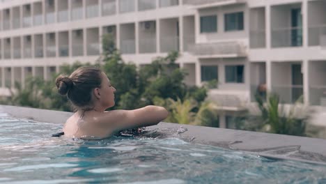 lady-in-black-bikini-swims-against-long-high-resort-hotel