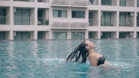 lady-in-bikini-splashes-water-with-hair-in-pool-slow-motion