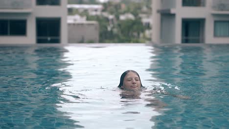 smiling-lady-emerges-from-water-in-swimming-pool-slow-motion