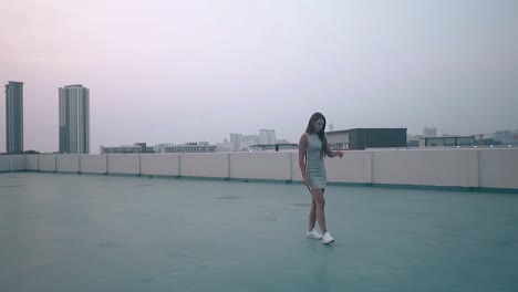 young-woman-in-dress-walks-along-roof-in-evening-slow-motion