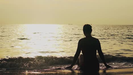Silhouette-Eines-Mädchens,-Das-Bei-Sonnenuntergang-In-Zeitlupe-Auf-Der-Surflinie-Sitzt