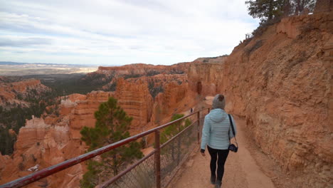 Frau-Geht-Auf-Einem-Wanderweg-Mit-Atemberaubender-Aussicht-Auf-Die-Landschaft-Des-Bryce-Canyon-Nationalparks,-Zeitlupe,-Rückansicht