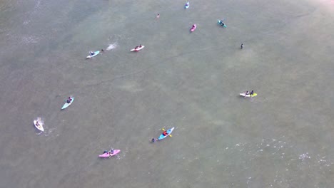 Aerial-shot-of-people-kayaking-on-the-ocean-near-the-beach-in-Indonesia