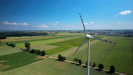 Windkraftanlage-Dreht-Sich-Vor-Grünen-Feldern-Und-Blauem-Himmel