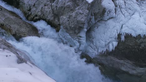 Wasser-Fällt-Im-Winter-Von-Bergklippen-Zwischen-Gefrorenen-Gebirgsketten-Und-Plätschert-Auf-Felsigen-Hängen