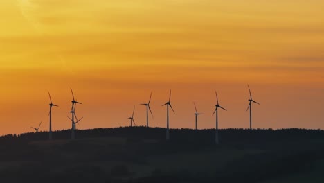 Silhouette-Von-Windkraftanlagen,-Die-Sich-Nach-Sonnenuntergang-Unter-Gelbem-Himmel-Drehen,-Grünes-Energiekonzept