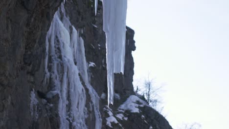 Frozen-splashes,-white-sharp-ice-floes-of-icicles-on-surface-of-rock-near-the-mountain-waterfall