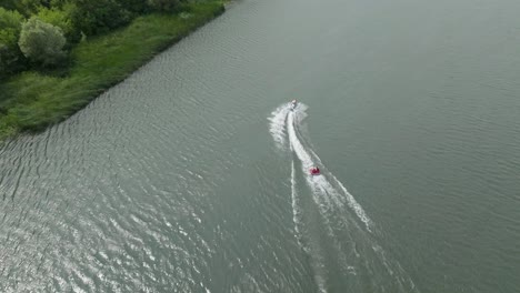 top-view-of-a-fast-moving-inflatable-boat-being-pulled-by-a-jet-ski-on-the-river