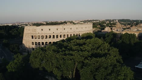 Drone-shot-pushing-towards-the-Roman-Colosseum-surrounded-by-trees