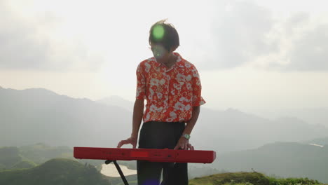 Asian-keyboard-player-at-mountain-in-Vietnam,-orbital-handheld
