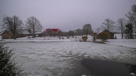 Timelapse---Overcast-clouds-over-countryside-houses-with-frozen-lake