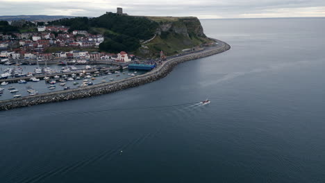 Establishing-Drone-Shot-Over-Scarborough-Bay-and-Harbour-with-Boat-Leaving-on-Overcast-Morning