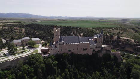 Scenic-drone-view-of-Alcazar-de-Segovia,-nestled-in-lush-nature