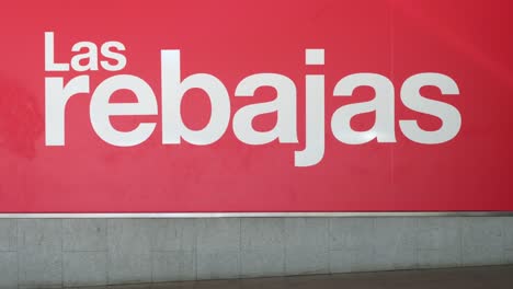 Pedestrians-and-shoppers-walk-past-a-large-banner-announcing-the-Summer-sale-season-outside-the-Spanish-biggest-department-store-El-Corte-Ingles-in-Spain