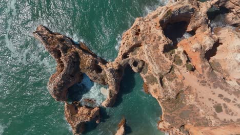 Jagged-rocky-eroded-coastline-of-lagos-algarve-portugal-ocean-waves-crashing,-aerial