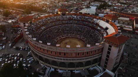 Flying-away-from-the-Plaza-de-Toros-stadium,-sunny-evening-in-Mexico---Aerial-view