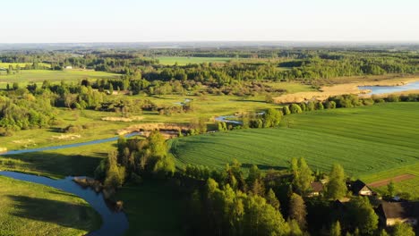 Panoramic-cropland-agriculture-field-surrounded-by-river-bend,-serene-aerial