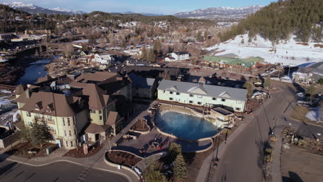 Aerial-View-of-Pagosa-Springs,-Colorado-USA-and-Hot-Geothermal-Water-in-Spa-Resort-on-Sunny-Winter-Day,-Revealing-Drone-Shot